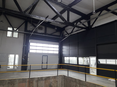 Perete despărțitor din PVC pe schelet metalic și ușă sectională cu panou vitrat culoare gri antracit in hala industrială.